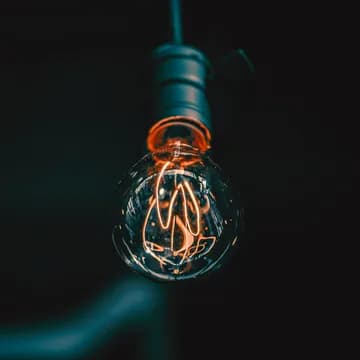 A hanging, glowing bulb with a darkish background.